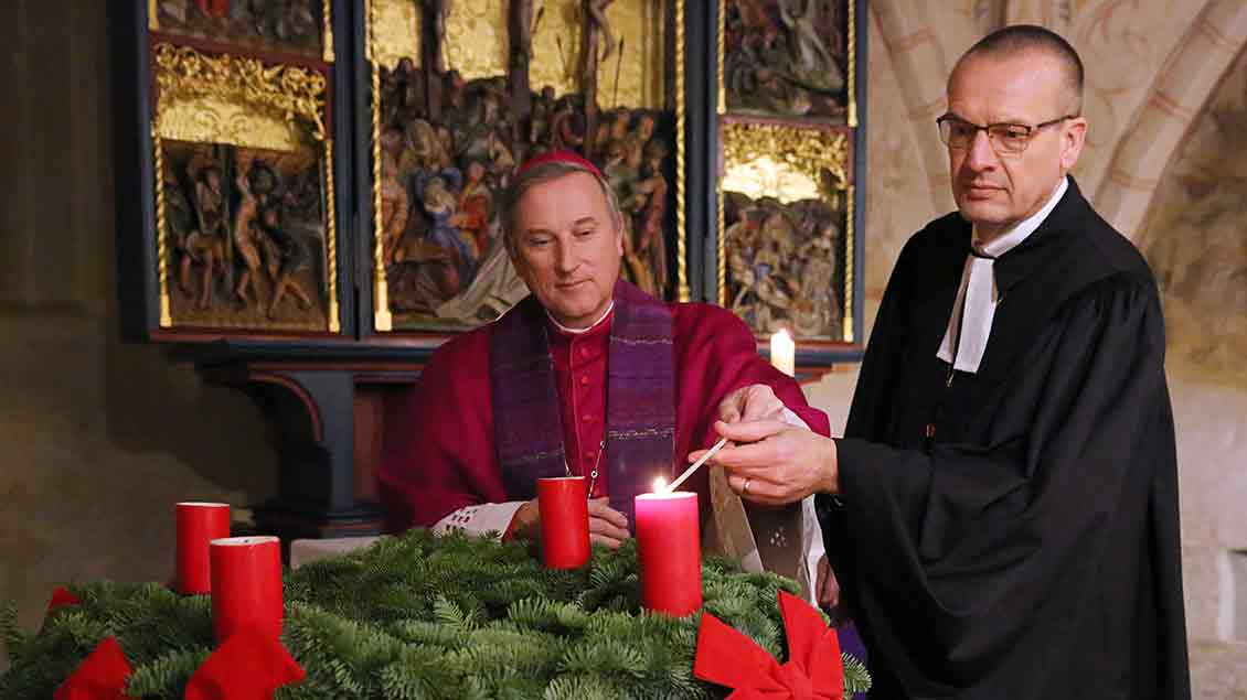 Weihbischof Wilfried Theising (links) und der evangelische Landesbischof von Oldenburg, Thomas Adomeit, entzünden bei einem ökumenischen Gottesdienst in Stuhr die erste Kerze am Adventskranz.