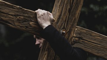 Ein Mann trägt ein Holzkreuz