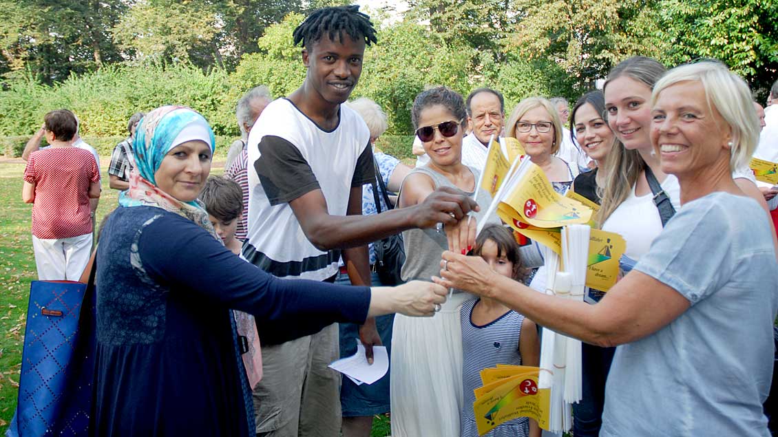 Im Kevelaerer Marienpark verteilten die Initiatoren Fähnchen als identitätsstiftendes Zeichen an die Teilnehmer der zweiten Interreligiösen Friedenswallfahrt.