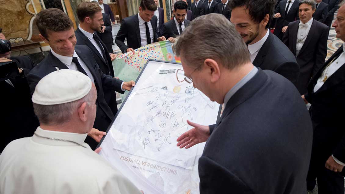 Die Spieler Thomas Müller (links) und Mats Hummels (rechts) überreichen Papst Franziskus ein signiertes Trikot der deutschen Fußballnationalmannschaft.