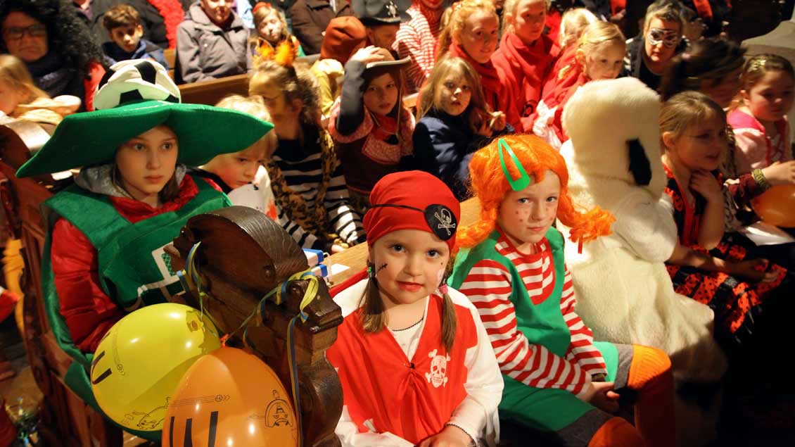 Kinder mit farbenprächtigen Kostümen füllen in der Karnevalsmesse die Bänke in der Rheinberger Kirche St. Peter. 