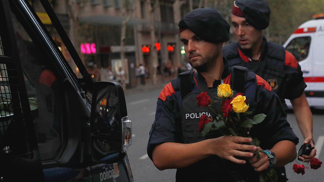 Eine Geste für den Frieden: Spanische Polizisten halten Rosen, die sie von den Demonstranten am Samstag in Barcelona geschenkt bekommen haben.