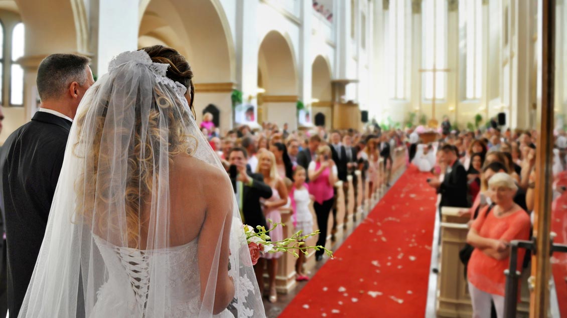 Ein Brautpaar zieht zur Trauung in eine Kirche ein.