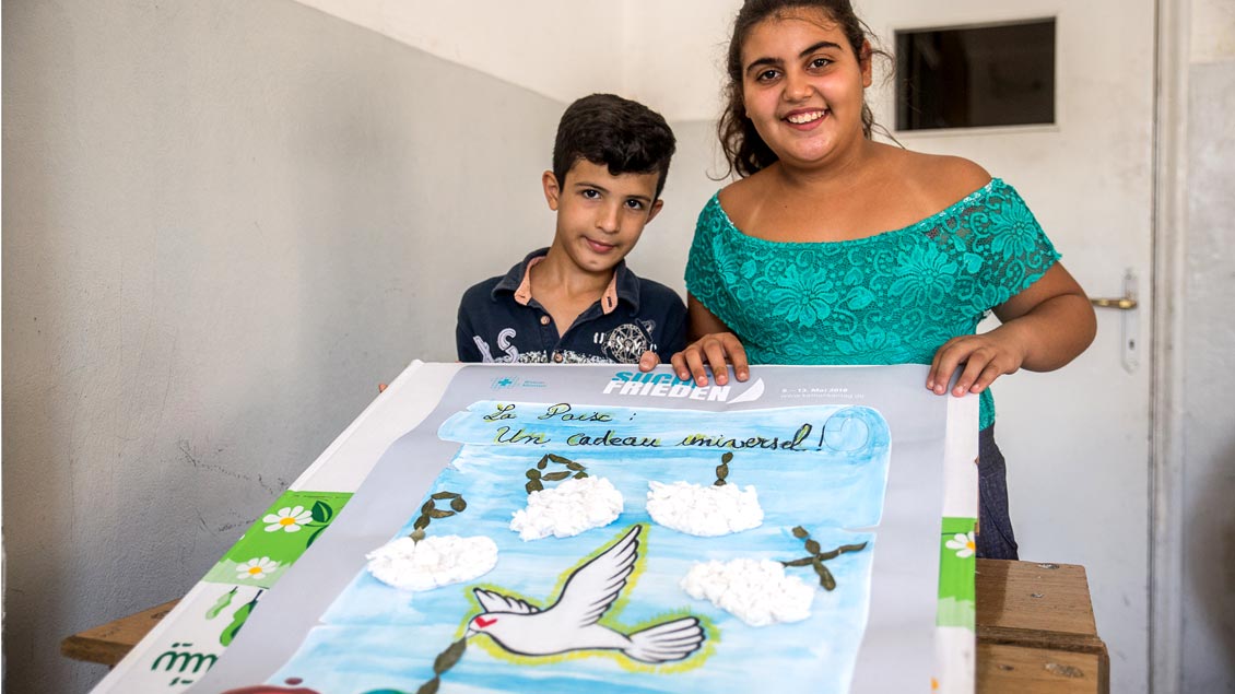 „Frieden - ein universelles Geschenk“ steht auf dem Plakat dieser beiden syrischen Flüchtlingskinder.