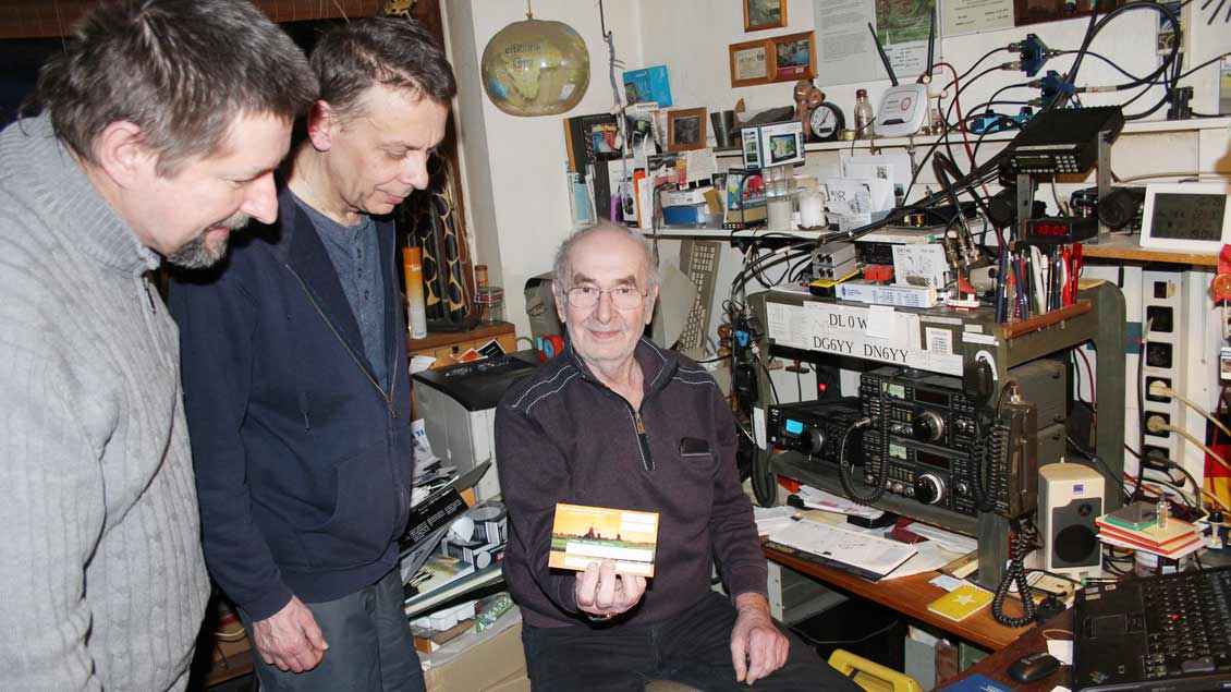 Diethard Klinkenberg (rechts) aus Münster-Nienberge zeigt an seiner Funkstation den Amateurfunkern Christian Reichert (links) und Thomas Groppe eine QSL-Karte. Mit dem Versand einer QSL-Karte bestätigen Funkamateure eine erfolgreiche Funkverbindung.