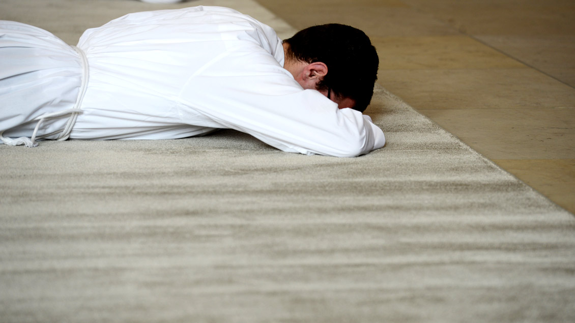 Ein Priesterkandidat liegt während der Weihe betend auf dem Boden.
