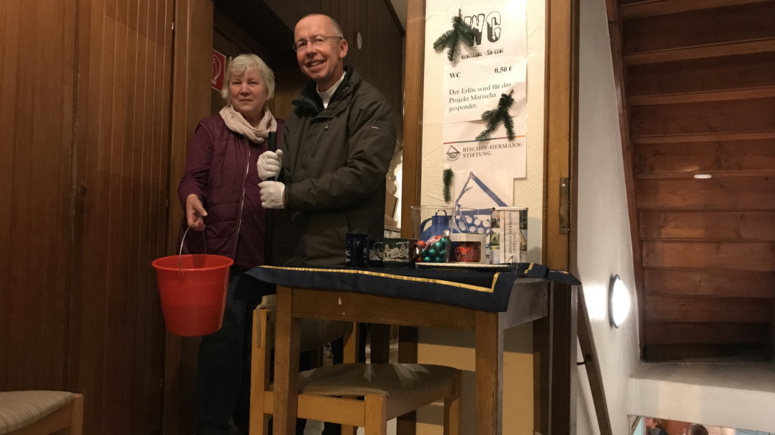 Gertrud Barlag von der katholischen Frauengemeinschaft und Pfarrer Peter Kossen putzen die Toiletten auf dem Weihnachtsmarkt in Leeden.