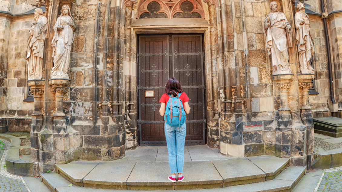 Eine Frau steht vor einer geschlossenen Kirchentür.