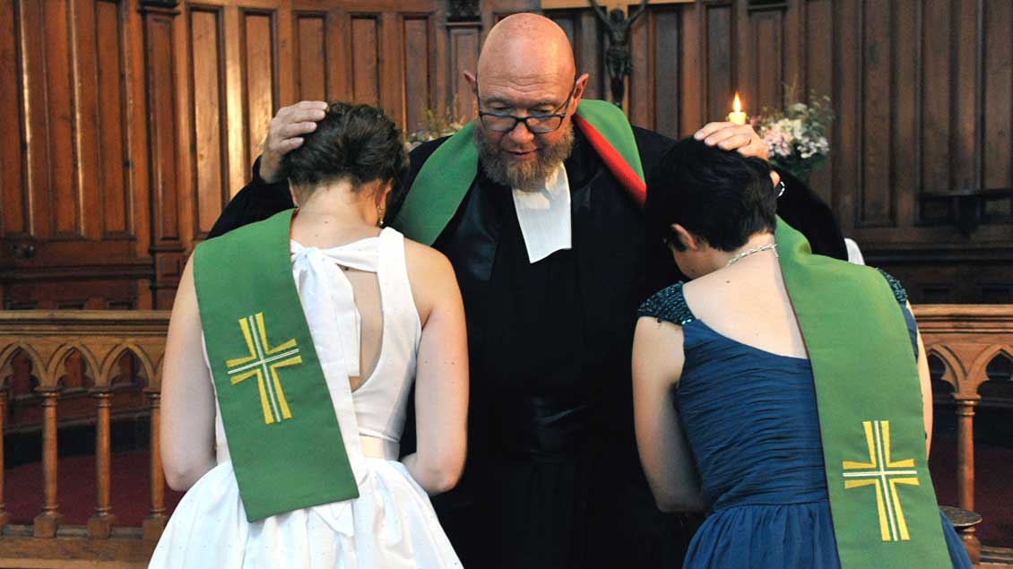 Ein protestantischer Pastor segnet zwei Bräute.