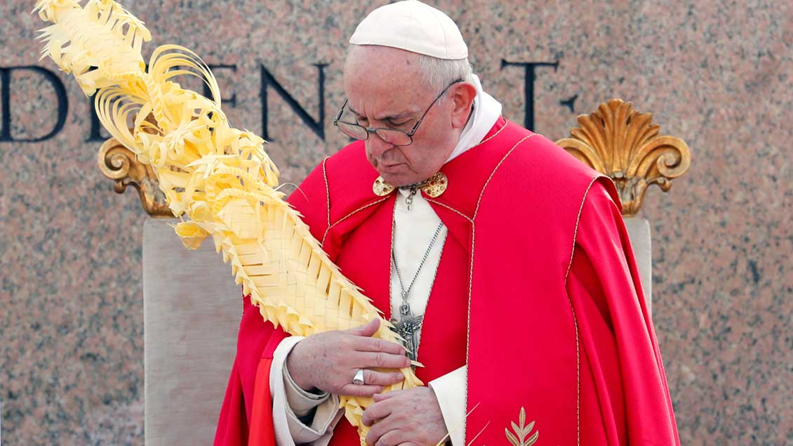 Papst Franziskus hält einen großen Palmzweig in den Händen.