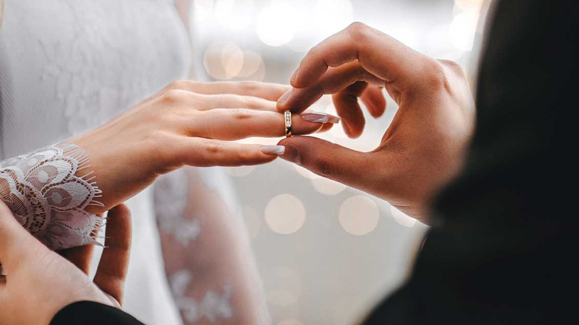 Ein Brautpaar steckt einander die Ringe an.