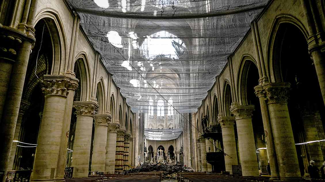 Blick von unten durch ein Sicherheitsnetz durch das zerstörte Dach von Notre Dame