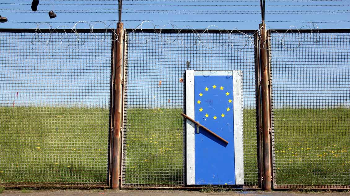 Symbolische Tür mit Europaflagge vor einem Stacheldrahtzaun