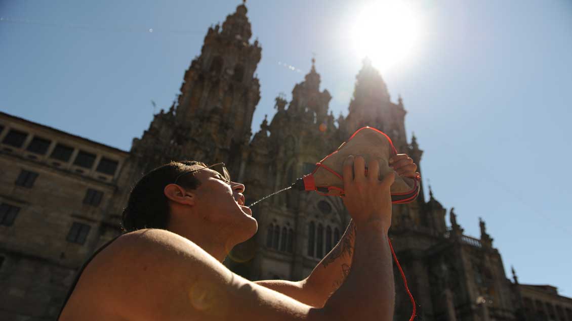 Pilger in Santiago de Compostela trinkt in der Sonne Wasser