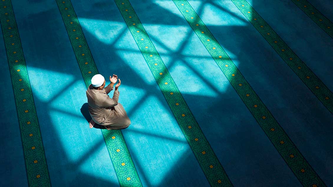Ein Muslim betet mit nach oben geöffneten Händen 