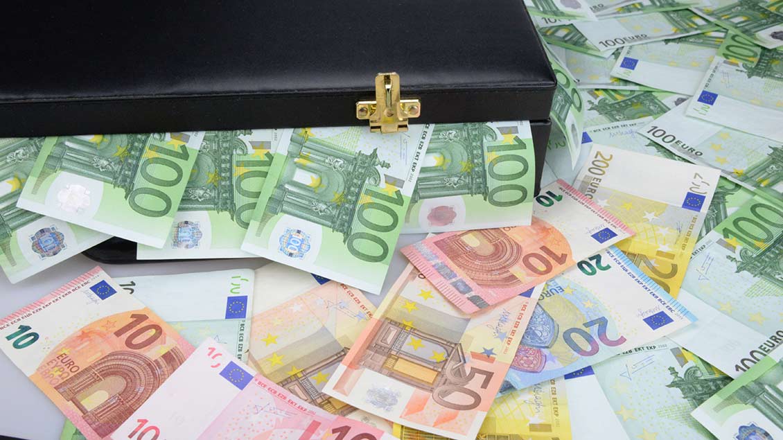 Aus einem schwarzen Geldkoffer kommen viele Euro-Scheine.