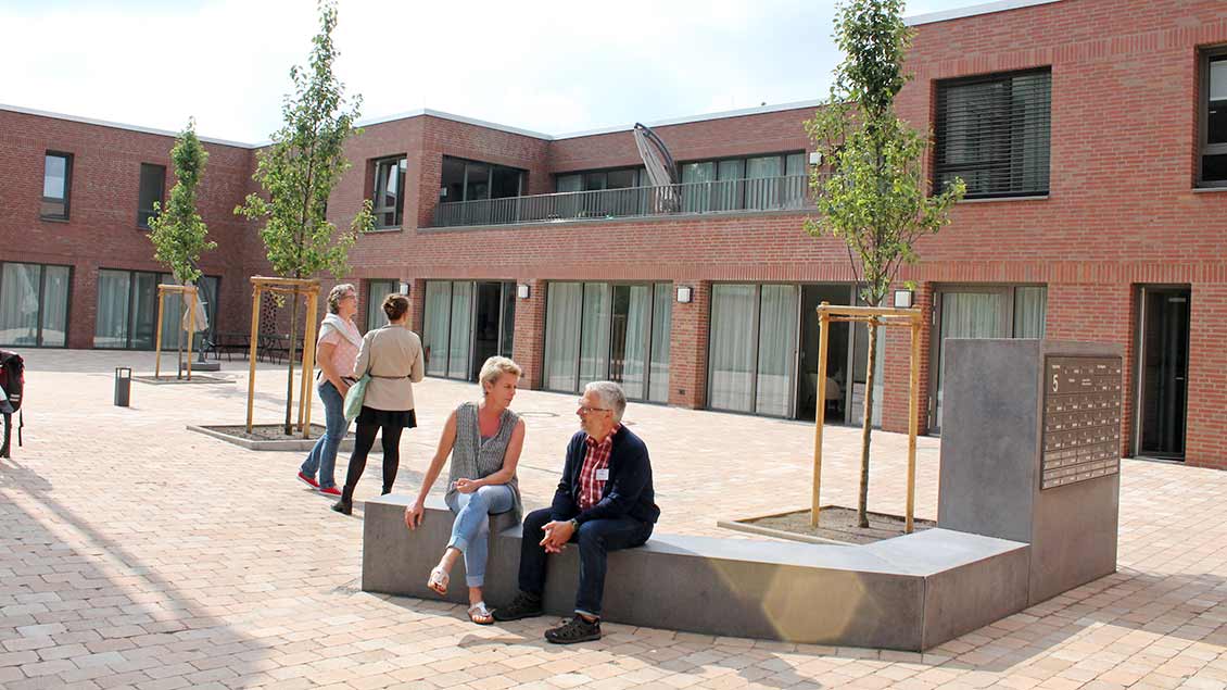 Hausleiterin Anke Flender und Pastoralreferent Ludger Picker sitzen vor dem Neubau auf einer Bank.. 