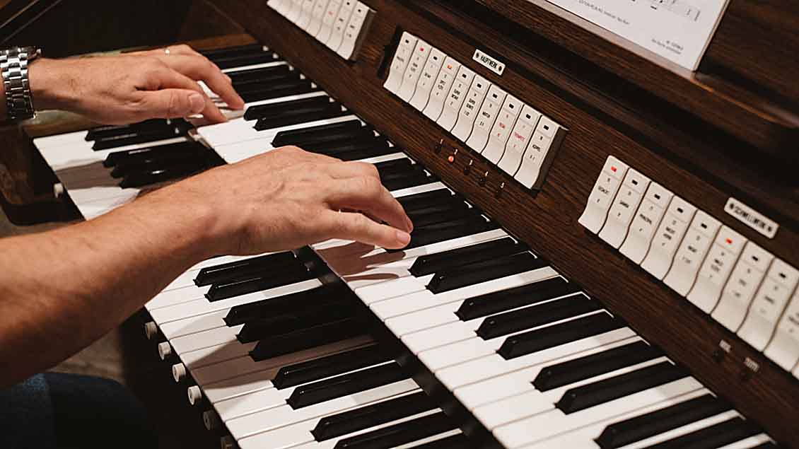 Hände eines Orgelspielers auf einer Orgel