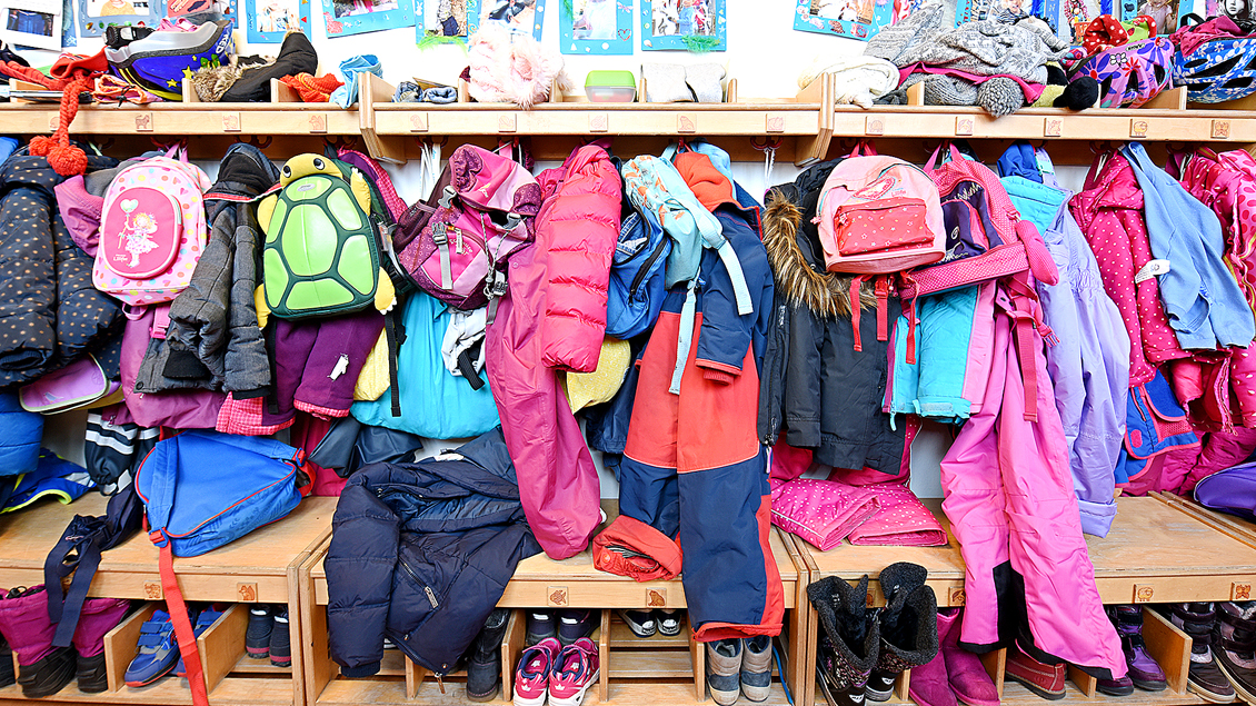Eine Garderobe in einem Kindergarten voller Anoraks, Stiefel und Fahrradhelme.