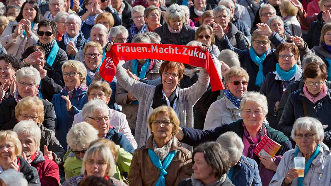 Münster 2018: Eine Frau inmitten vieler Frauen hält den KFD-Kampagnen-Schal in die Kamera.