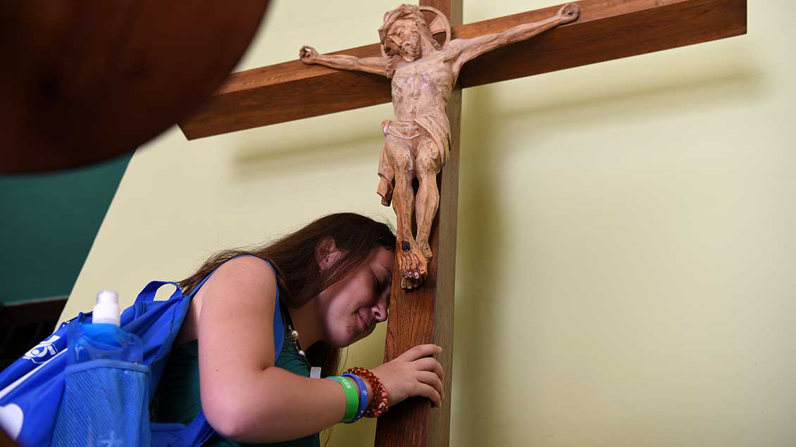 Junge Frau vor einem Kreuz