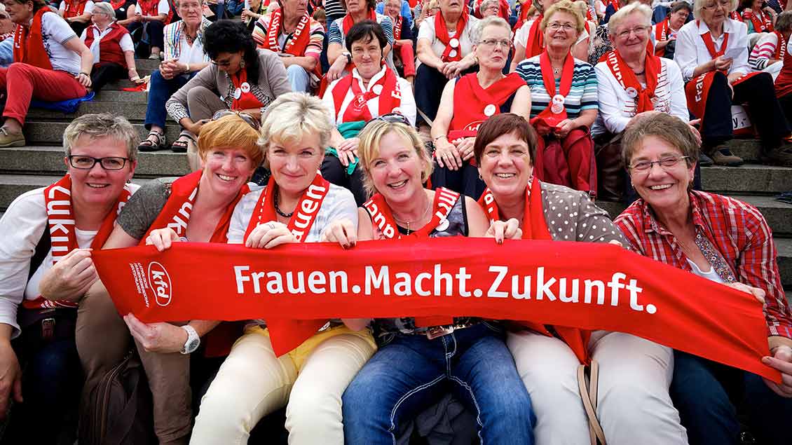Frauen halten einen roten Schal mit dem Motto der Mitglieder-Werbekampagne "Frauen.Macht.Zukunft" hoch.