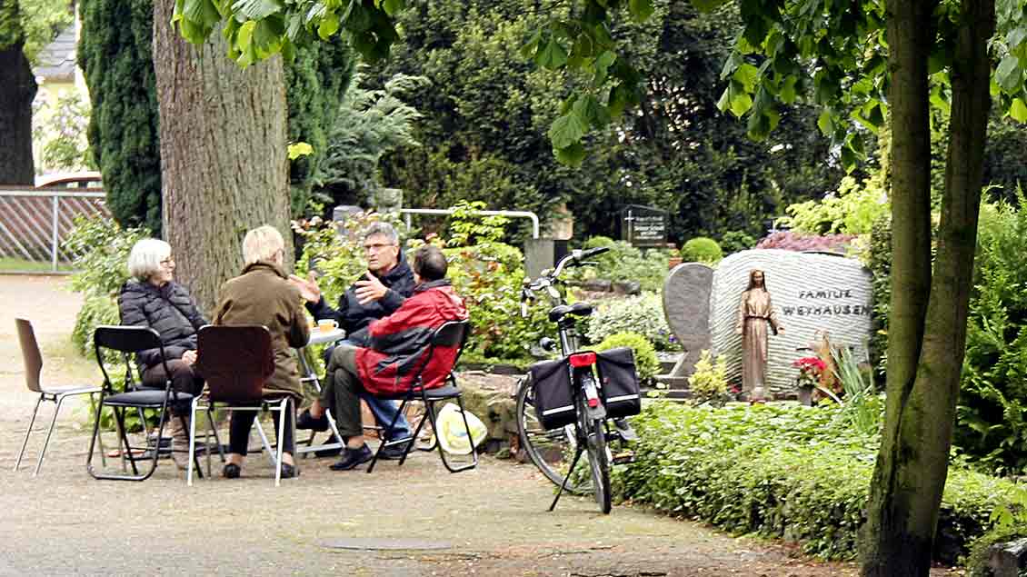 Eine Gruppe von Menschen sitzt auf Klappstühlen auf dem Katholischen Friedhof in Oldenburg zusammen. Das Projekt dort heißt "Café der Erinnerung".