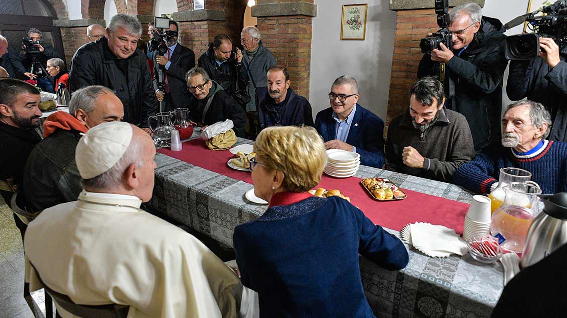 Der Papst sitzt am Tisch in der Obdachlosenunterkunft im Palazzo Migliori.
