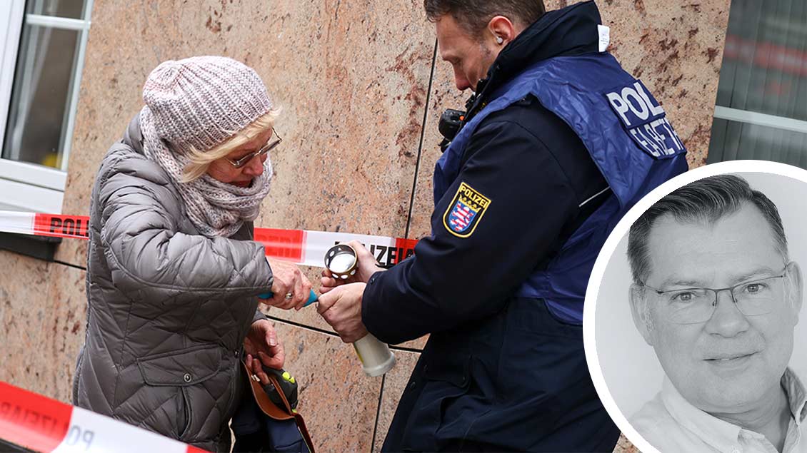 Ein Polizist hilft einer Frau in Hanau, eine Kerze anzuzünden.
