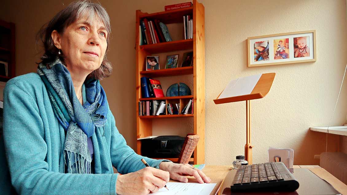 Lisa Oesterheld sitzt vor einem Schreibblock zu Hause an ihrem Schreibtisch.
