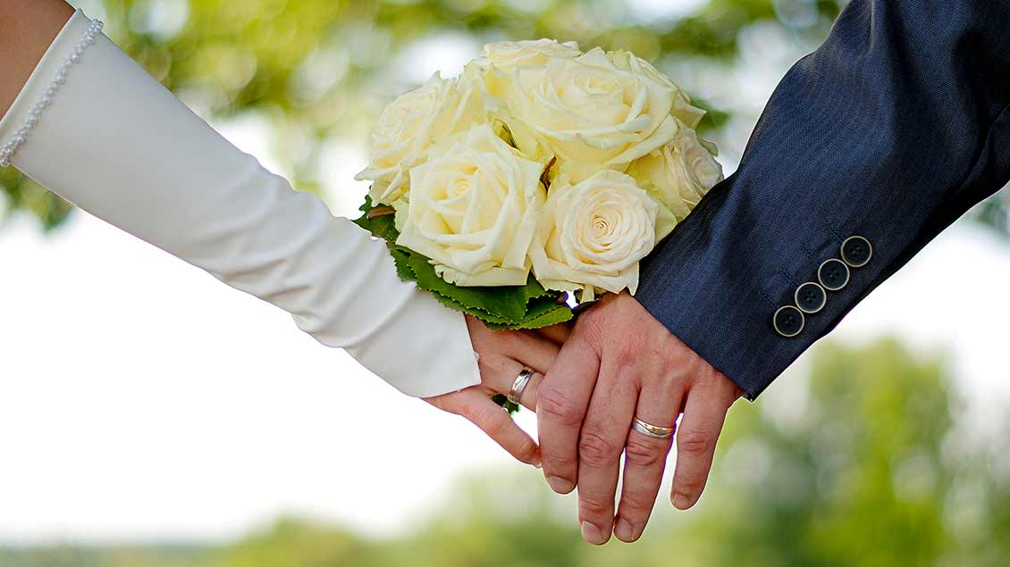 Ein Hochzeitspaar hält sich an den Händen. Das Zeichen, dass beide die Liebe gefunden haben.