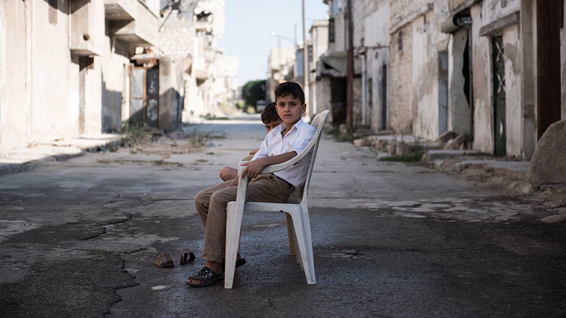 Ein Junge auf einer Straße mit zerstörten Häusern in Syrien
