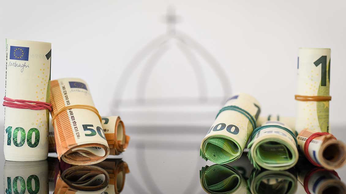 Geld vor einem Kirchensymbol