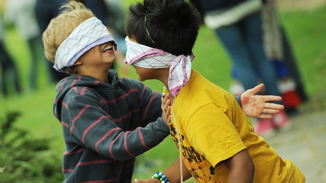 Zei Kinder spielen mit verbundenden Augen während einer Ferienfreizeit.