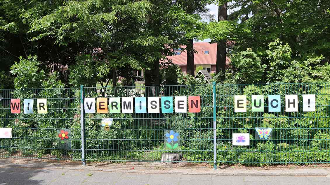Kindergartenzaun mit Aufschrift „Wir vermissen Euch“