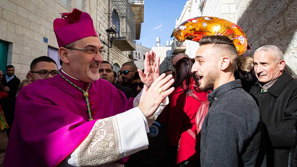 Pierbattista Pizzaballa begrüßt Passanten bei der Prozession zum Krippenplatz vor der Geburtskirche am Heiligabend 2019.