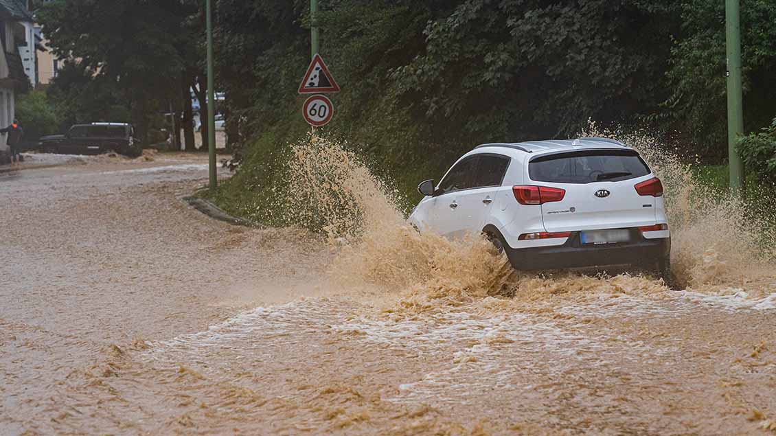 Ein Auto führt über eine überflutete Fahrbahn