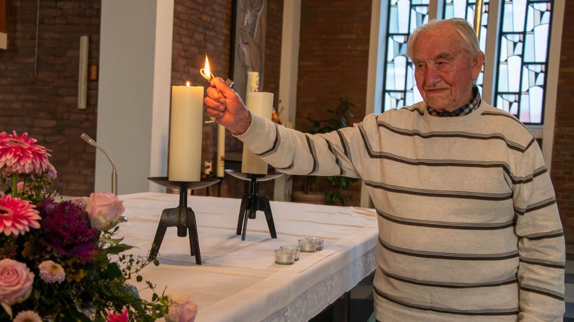 Ein Mann zündet eine Kerze auf einem Altar an.