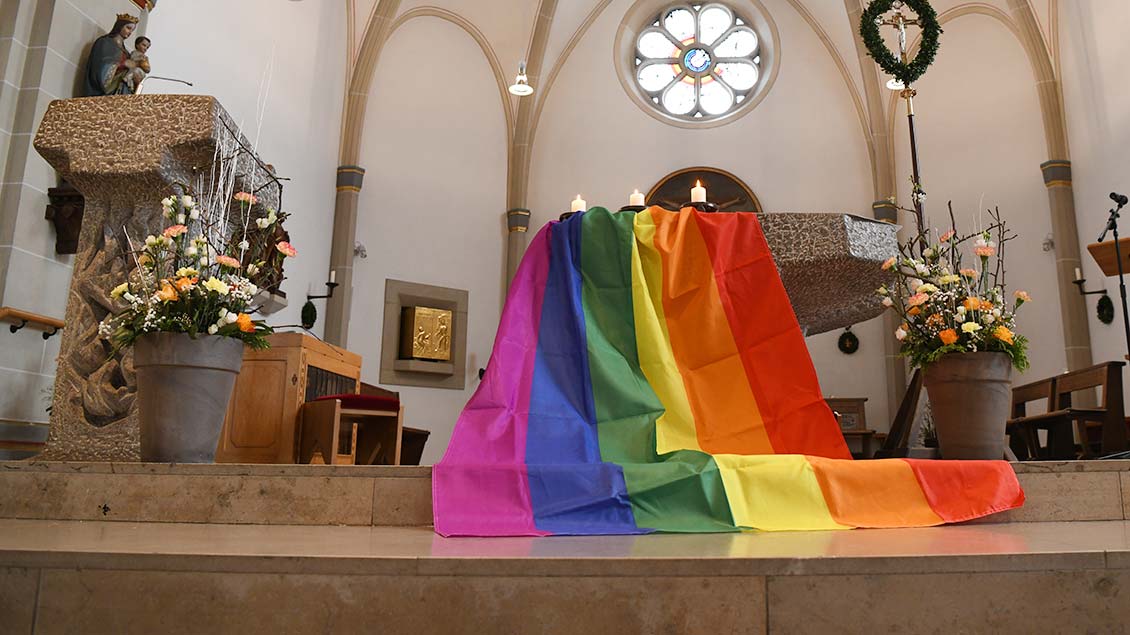 Eine Regenbogenflagge an einem Altar.