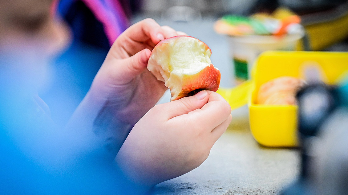 Kinderhände halten einen Apfel