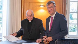 Bischof Felix Genn und Uni-Rektor Johannes Wessels unterzeichnen den Vertrag zur Studie. | Foto: Christof Haverkamp