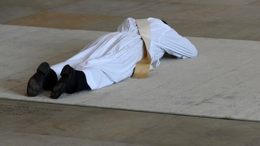 Ein Neupriester liegt bei seiner Weihe auf dem Boden