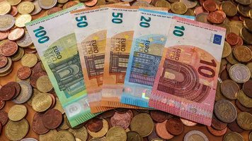 Haufen von Euro-Münzen und Geldscheinen