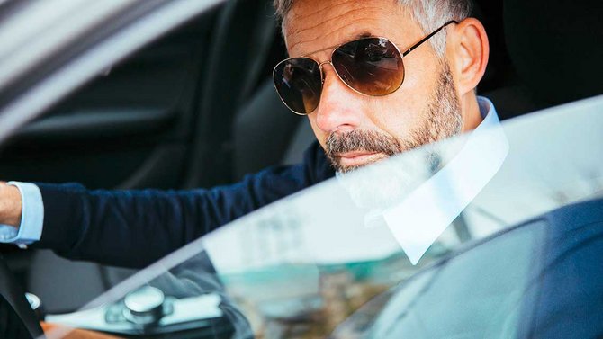 Mann mit Sonnenbrille im Auto sitzend