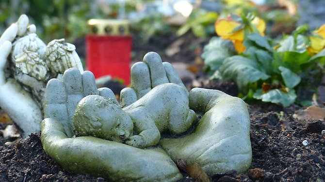 Grabstein: Zwei Hände halten ein Baby