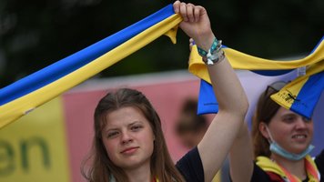 Eine Frau hält eine blau-gelbe Fahne in die Luft.