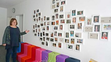 Ina Kasten Kisling vor der Wand mit den Fotos der rund 100 ehrenamtlichen Hospizbegleiter.