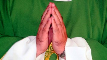 Priester faltet die Hände zum Gebet