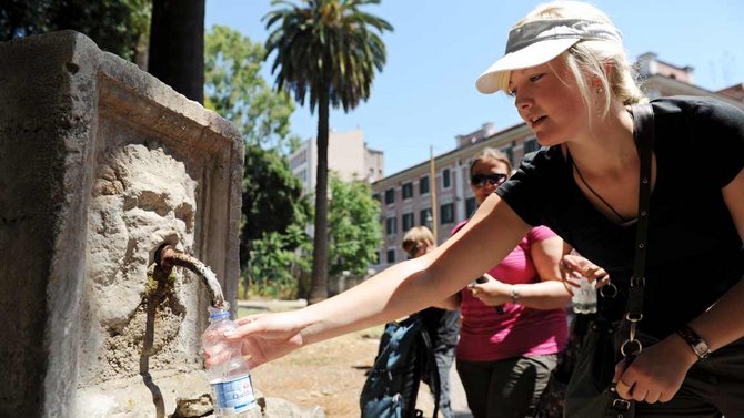 Wasserzapfen aus einem öffentlichen Trinkbrunnen in der Hitze Roms.
