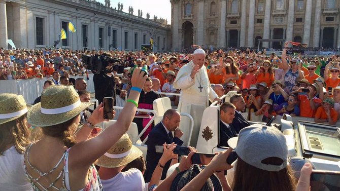 Papst Franziskus winkt auf dem Petersplatz jungen Menschen zu.
